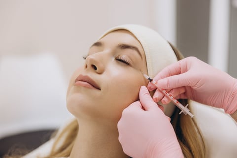 Skilled cosmetologist performing anti aging injection treating patient facial wrinkles